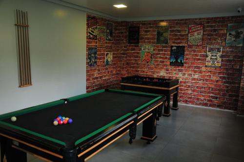 a room with a pool table and a brick wall at Casa Jardins da Lagoa in Caldas Novas