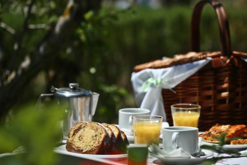 a table with a basket of bread and glasses of orange juice at Dendrolivano in Minia