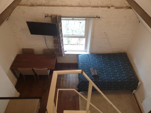 a room with a bed and a desk and a window at Mezzanine studio apartment (U9) in London
