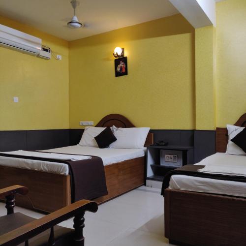 two beds in a room with yellow walls at Arudhra Residency in Chidambaram