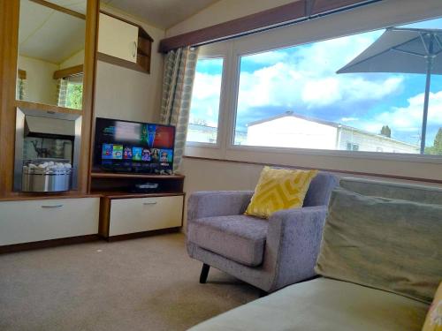 sala de estar con silla, TV y ventana en Eden Breaks, Mallard Lake, en Cirencester