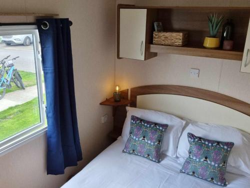 a bedroom with a white bed with a window at Eden Breaks, Mallard Lake in Cirencester