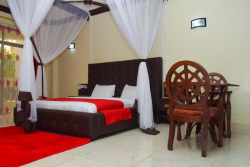 1 dormitorio con 1 cama con manta roja y sillas en White Peacock Resort Mtwapa en Mtwapa