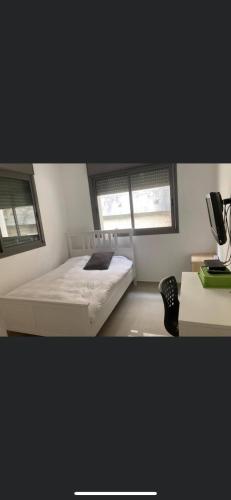 1 dormitorio con 1 cama, escritorio y 2 ventanas en מורדות עין כרם en ‘En Kerem