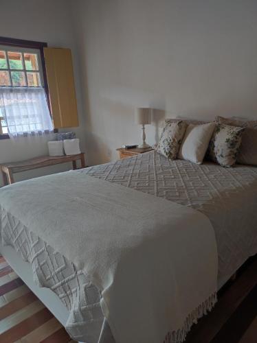 a large bed in a bedroom with a window at Pedacinho do céu in Tiradentes