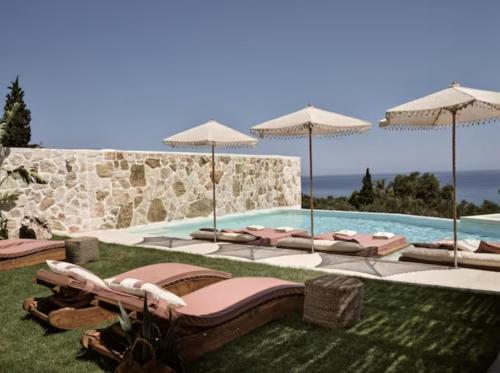 a pool with a bunch of chairs and umbrellas at Ismet Villa, a SeaView Glorious Hideaway, By ThinkVilla in Akrotiri