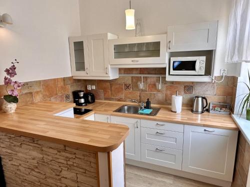 a kitchen with white cabinets and a sink and a microwave at Pension SKLEP in Prague