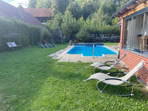 a group of chairs sitting in the grass by a pool at Apartmán Beruška in Křelovice