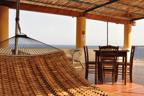 a hammock on a patio with a table and chairs at Albergo Seaside in Leni