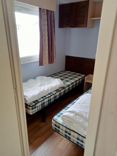 two beds in a small room with a window at Stacaravan met eigen terras en tuin 6personen in Bredene