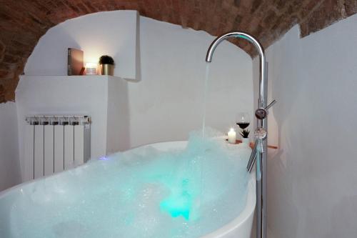 La salle de bains est pourvue d'une baignoire remplie d'eau bleue. dans l'établissement Medieval flat with whirlpool bath, à Pérouse