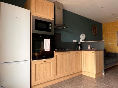 une cuisine avec des armoires en bois et un réfrigérateur blanc dans l'établissement les gîtes du péré, à Soubise
