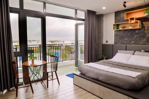 a bedroom with a bed and a table and a balcony at Cherry Hotel Bến Lức in Bến Lức