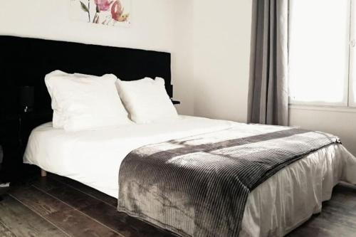 um quarto com uma cama branca e uma cabeceira preta em Magny en Vexin : Maison meublée em Magny-en-Vexin