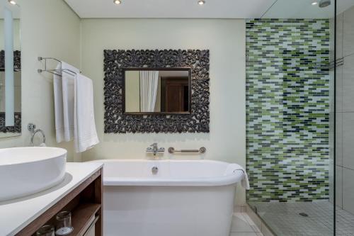 a bathroom with a tub and a sink and a mirror at Protea Hotel by Marriott Upington in Upington