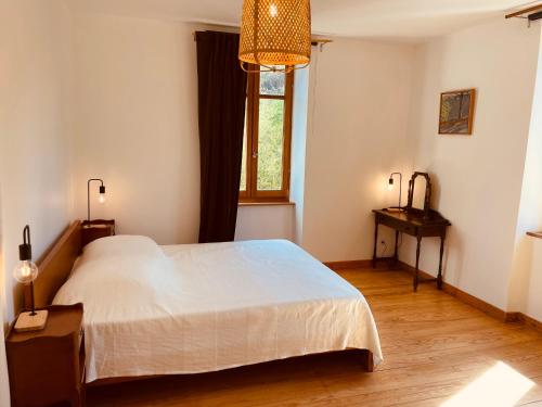 une chambre avec un grand lit blanc et une fenêtre dans l'établissement Maison de famille et d'ami·e·s, à Valady