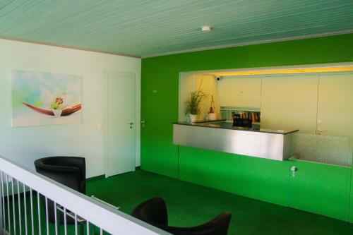 a lobby with green walls and chairs and a counter at Hotel Alpha in Stuttgart