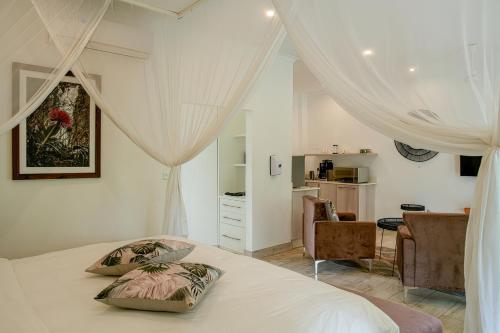 a bedroom with a bed with curtains and a desk at Pristine deluxe room with kitchen and pool - 2147 in Victoria Falls