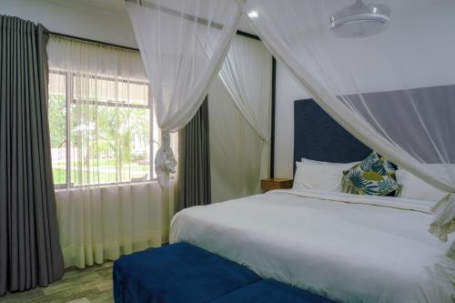 um quarto com uma cama branca e uma janela em Modern deluxe with kitchenette and pool - 2148 em Victoria Falls