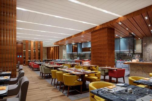 a dining room with tables and yellow chairs at Sheraton Petaling Jaya Hotel in Petaling Jaya