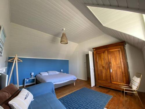 une chambre avec un lit et un canapé bleu dans l'établissement Maison bigoudène à 5 minutes de Pors Carn, à Penmarcʼh