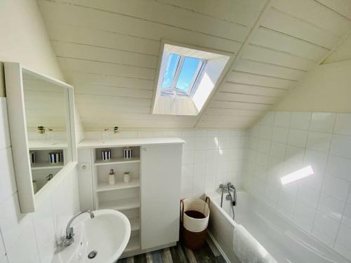 La salle de bains est pourvue d'un lavabo, d'une baignoire et d'une fenêtre. dans l'établissement Maison bigoudène à 5 minutes de Pors Carn, à Penmarcʼh