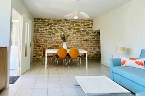 un salon avec un canapé bleu, une table et des chaises dans l'établissement Maison bigoudène à 5 minutes de Pors Carn, à Penmarcʼh