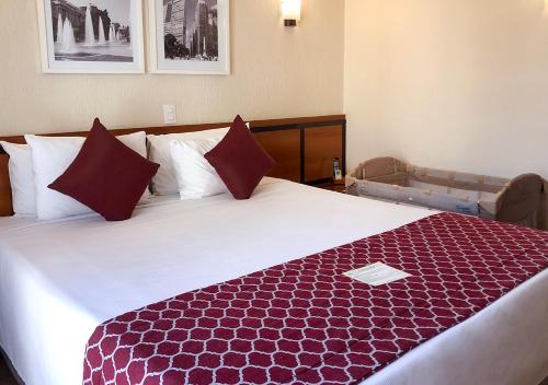 a hotel room with a large bed with red pillows at Leques Brasil Hotel Escola in Sao Paulo