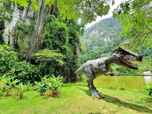 a statue of a dinosaur standing in the grass at IPOH All Suite Resort, Jalan Haven, Persiaran Lembah Perpaduan, Ipoh Perak in Ipoh