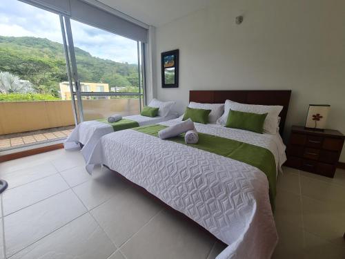 Duas camas num quarto com uma grande janela. em ACATA - Condominio Campestre / Casa em Villeta
