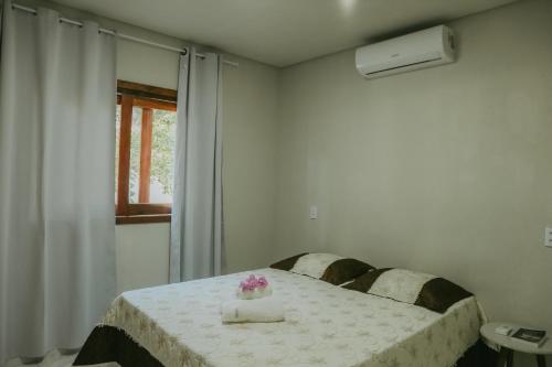a bedroom with a bed and a table with flowers on it at Vila hangloose pôr do sol in Aranaú