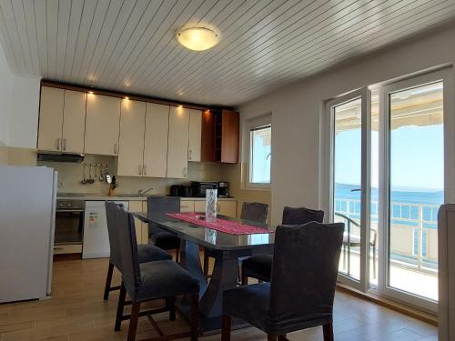 una cucina con tavolo e sedie e vista sull'oceano di Apartman Figaro sa dva kupatila uz more i plažu s pogledom na Split a Kaštela (Castelli)