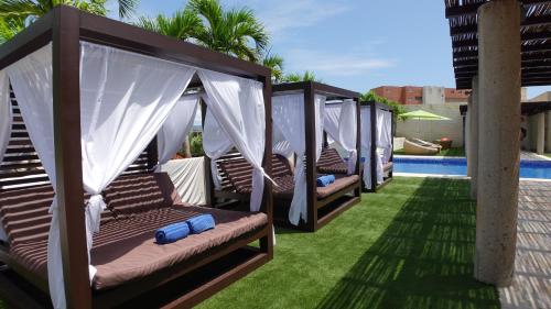 a row of wooden swings on a lawn next to a pool at SUNSOL UNIK Luxury Hotel in Porlamar