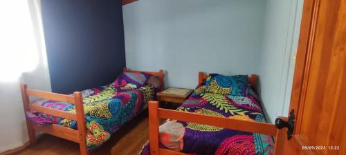 um quarto com duas camas com cobertores coloridos em Casa Loncura Quintero em Loncura