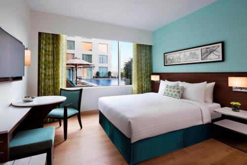 班加羅爾的住宿－班加羅爾外環路費爾菲爾德萬豪酒店，配有一张床、一张书桌和一扇窗户的酒店客房