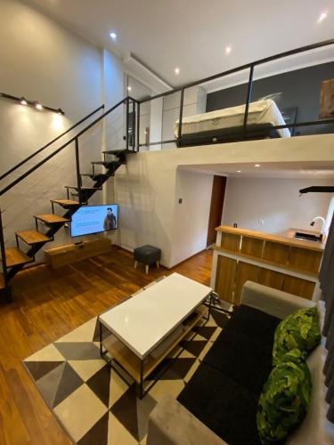 een woonkamer met een bank, een tafel en een trap bij Modern LOFT studio apartment in Sanur