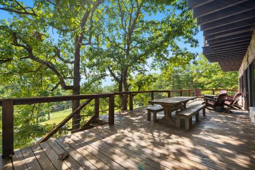 a deck with a picnic table and benches on it at Ozark Outdoor Legacy in Ridgedale