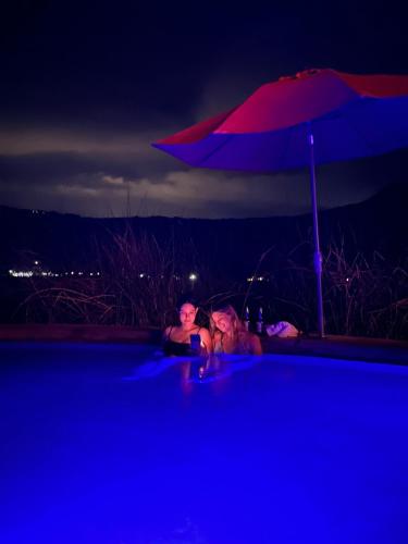 a couple of people sitting in a swimming pool with an umbrella at Punta Santa Maria in Santa María del Oro