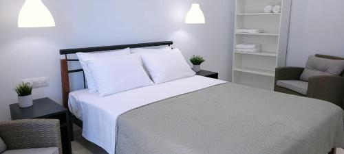 a bedroom with a bed with white sheets and two chairs at Crete Apart House - South in Ayía Marína