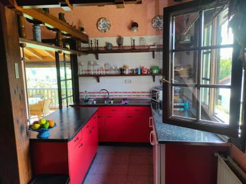cocina con armarios rojos y ventana grande en Casa Rural Maidanea, en Hondarribia