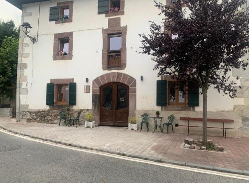 un edificio con puerta de madera, mesa y sillas en Apartamentos De Montaña Mendiola - Casa Ferran-Casa Karrikaburu, en Valcarlos