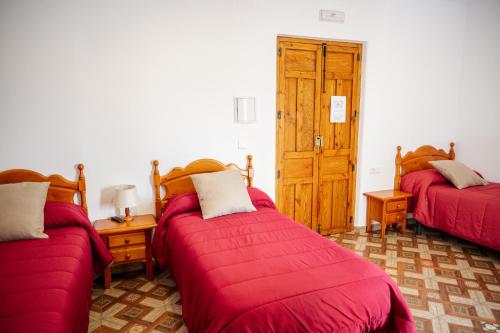 - une chambre avec 2 lits avec des couvertures rouges et une porte en bois dans l'établissement Rollo Campillo, à Trujillo