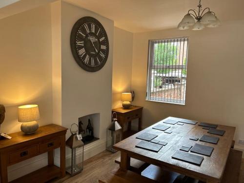 a room with a table and a clock on the wall at Beautiful 4BR Home near Chester Racecourse in Chester