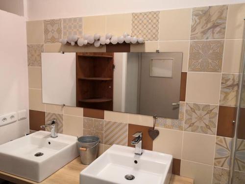 une salle de bain avec deux lavabos et un miroir dans l'établissement Maison avec piscine dans village provençal., à Courthézon