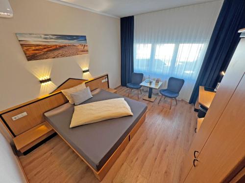 ショップハイムにあるHIL - Hotel im Lus Schopfheimのベッド、テーブル、椅子が備わる小さな客室です。