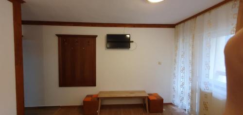 Habitación con mesa y TV en la pared. en Pensiunea Cota 1200 Piscul Negru en Arefu