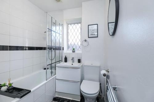 a white bathroom with a toilet and a sink at Lovely Two Bed at Tanglewood in Hillingdon
