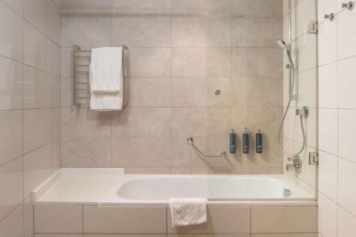 墨巴本的住宿－Hilton Garden Inn Mbabane，白色的浴室设有浴缸和淋浴。