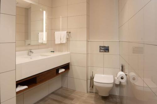 a white bathroom with a sink and a toilet at Hilton Garden Inn Mbabane in Mbabane