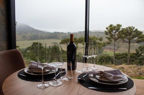 una mesa con una botella de vino y copas en Jardim das Pedras en Bom Jardim da Serra